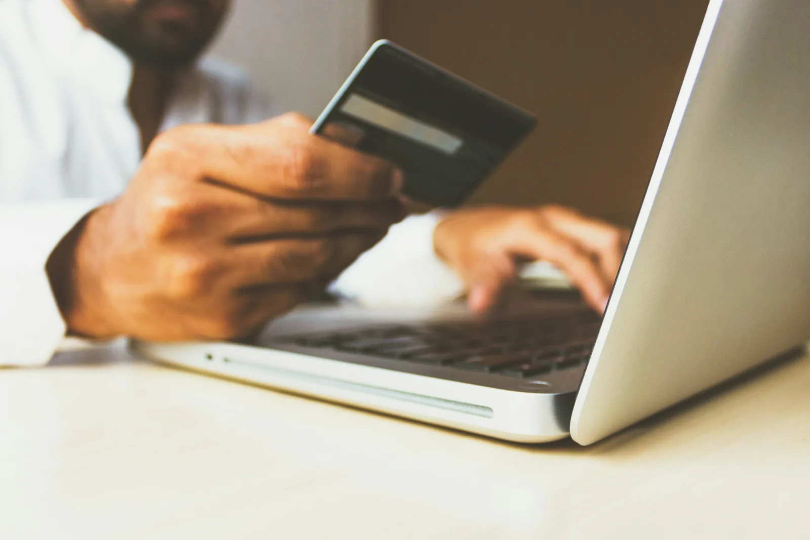 person working on laptop holding card - Add to Cart Conversion Rate